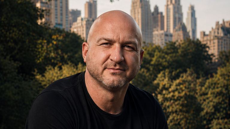 Nick Cavuoto seated outdoors in a dark editorial portrait.