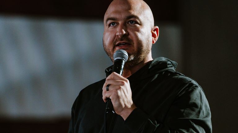 Nick Cavuoto speaking on stage with a microphone.