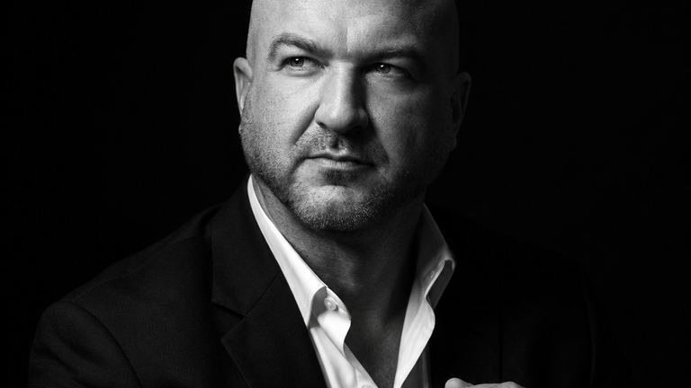 Nick Cavuoto in a dark suit, hands clasped.